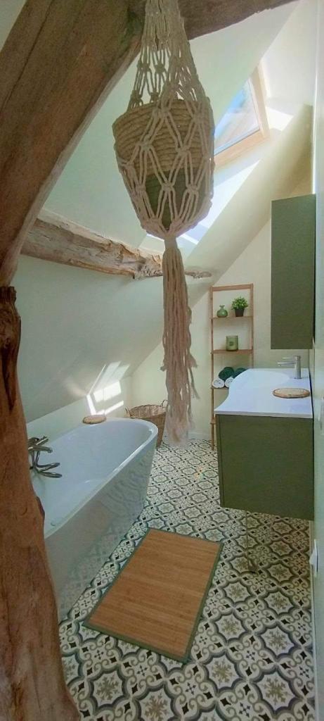 La salle de bains est pourvue d'une baignoire et d'un lustre. dans l'établissement Gîte Labonnechose, à Notre-Dame-de-Fresnay