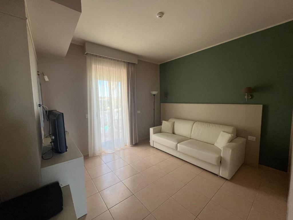 un salon avec un canapé blanc et une télévision dans l'établissement Mediterranean Boutique Hotel, à Tropea