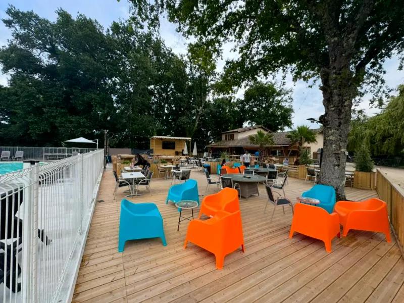 - un ensemble de chaises et de tables sur une terrasse en bois dans l'établissement Camping Les Franquettes - Aquatique Vacances, à Grayan-et-lʼHôpital