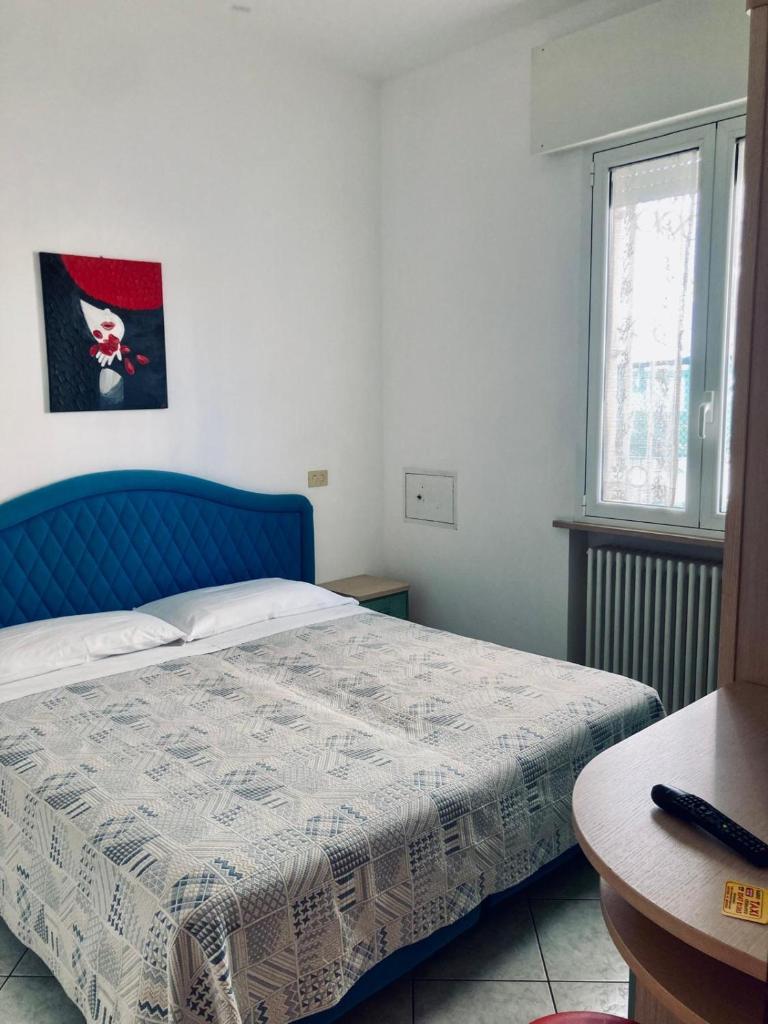 - une chambre avec un lit bleu et une table dans l'établissement Hotel President, à Cesenatico