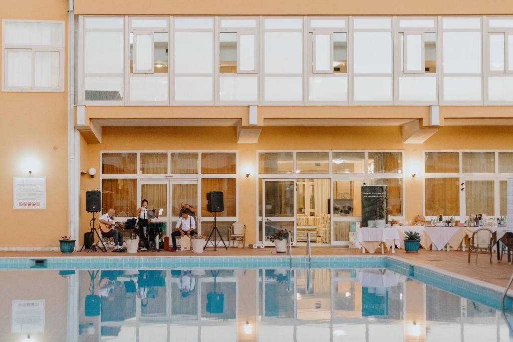 un groupe de personnes debout devant une piscine dans l'établissement Hotel Malaspina, à Bosa Marina
