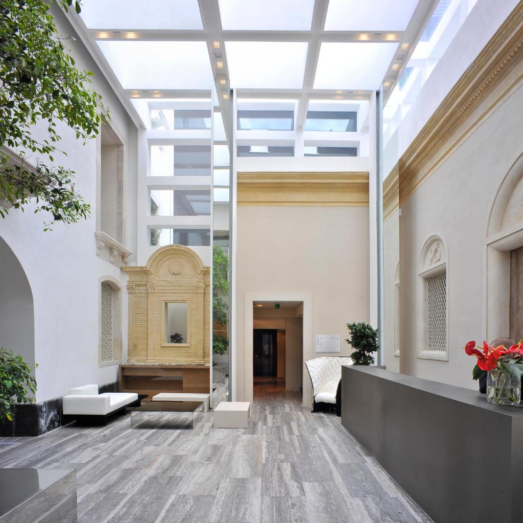 un hall vide avec un grand plafond de verre dans l'établissement Hotel Romano House, à Catane