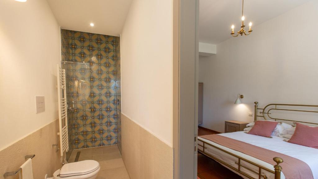 une salle de bain avec un lit et des toilettes dans une chambre dans l'établissement Casale Buccellato 14 by Massimo Villas, à Castellammare del Golfo