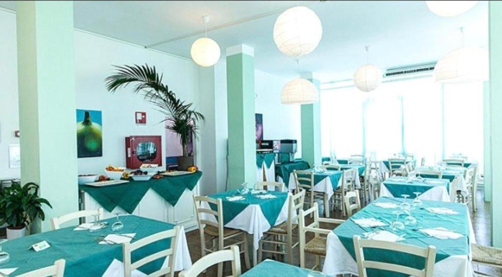 une salle à manger avec des tables bleues et des chaises blanches dans l'établissement Hotel Bruna, à Cesenatico