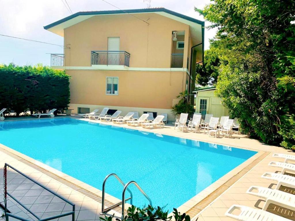 une grande piscine avec des chaises et un bâtiment dans l'établissement Hotel Bruna, à Cesenatico
