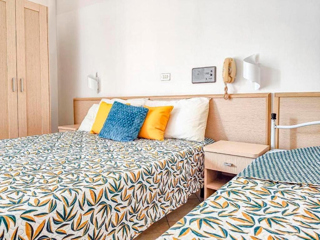 Cette chambre d'hôtel comprend 2 lits avec des oreillers colorés. dans l'établissement Hotel Bruna, à Cesenatico