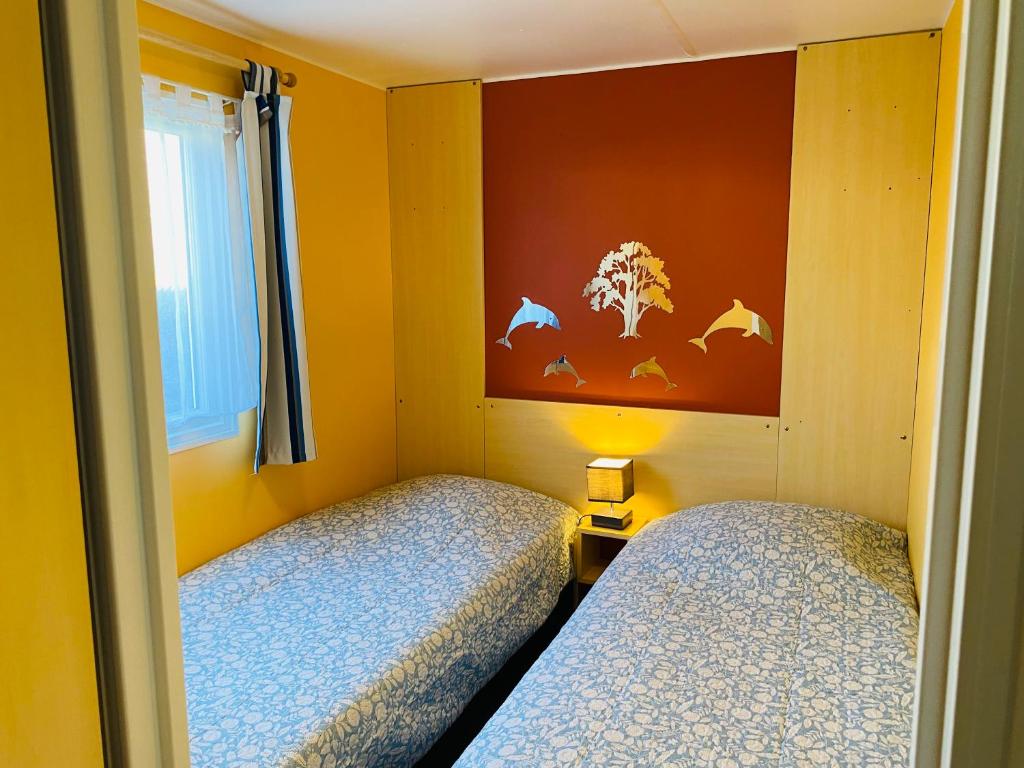 - 2 lits dans une petite chambre aux murs jaunes dans l'établissement Mobilhome Harmonie, à Biscarrosse