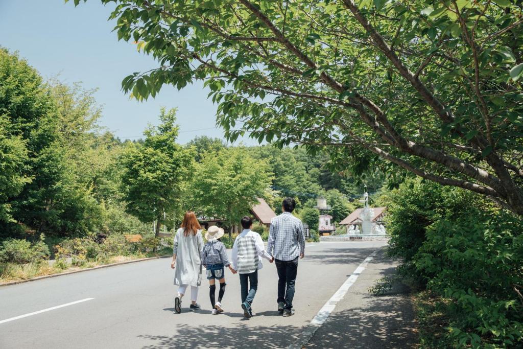 Une famille se promenant sur la route dans l'établissement Izumigo AMBIENT Yatsugatake Cottage, à Hokuto
