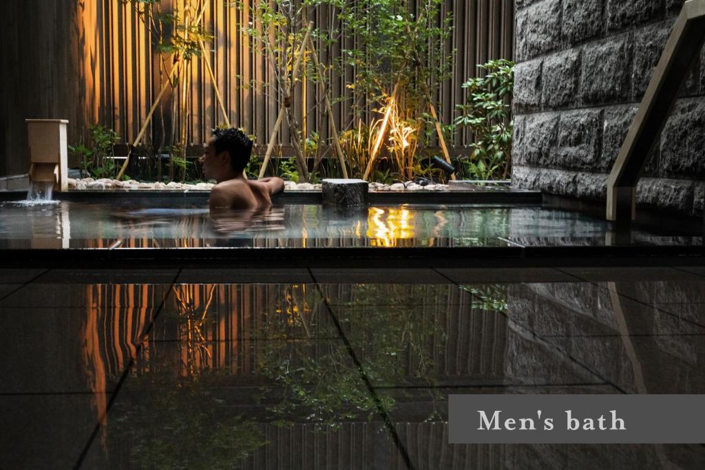 - un homme assis dans une baignoire au bord de la piscine dans l'établissement ONSEN RYOKAN Yuen Sapporo, à Sapporo