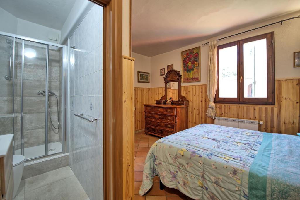 une chambre avec un lit et une douche en verre dans l'établissement Villa Mario by PosarelliVillas, à Lucignano