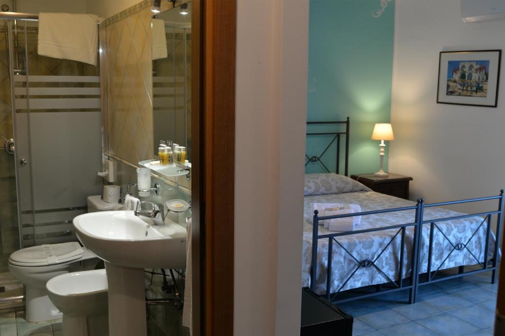 une salle de bain avec un lavabo et des toilettes et un lit dans l'établissement Hotel Donna Rosa, à SantʼAlessio Siculo