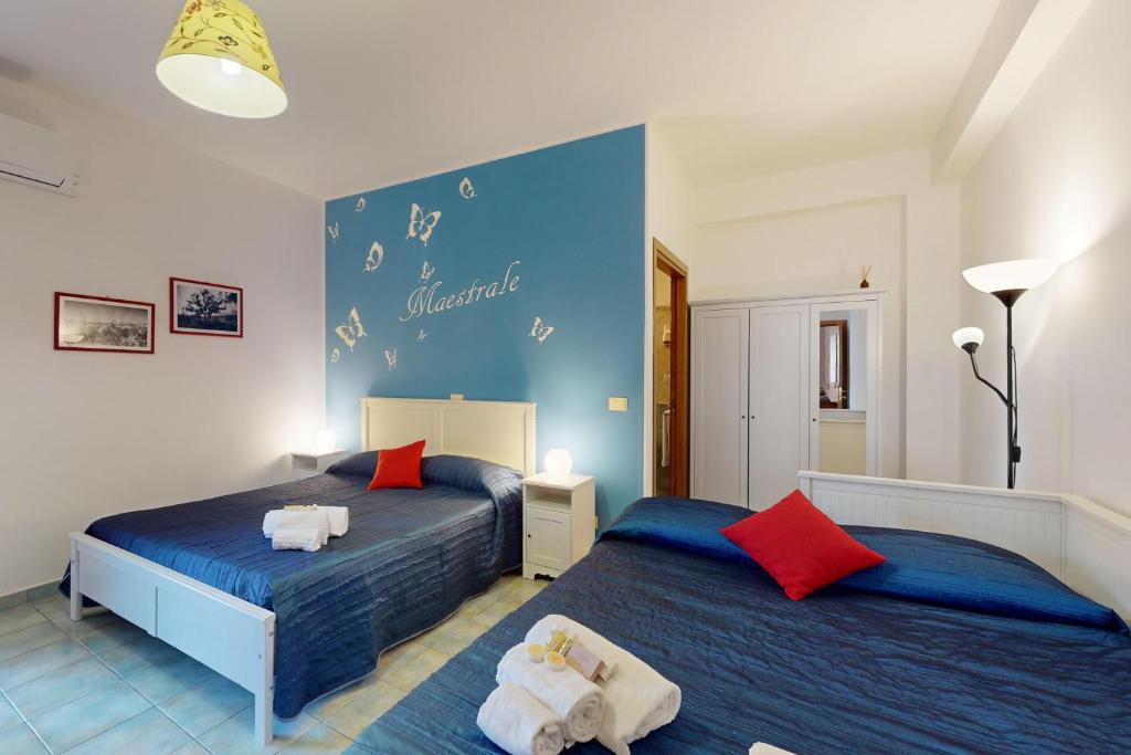 une chambre avec deux lits et un mur bleu dans l'établissement Hotel Donna Rosa, à SantʼAlessio Siculo