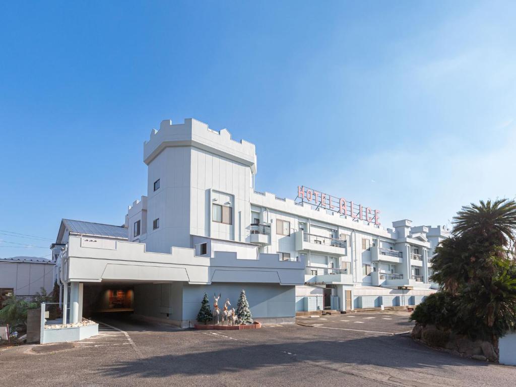 un grand bâtiment blanc avec des arbres devant lui dans l'établissement デザイナーズホテル アリス -Adult only-, à Sasebo