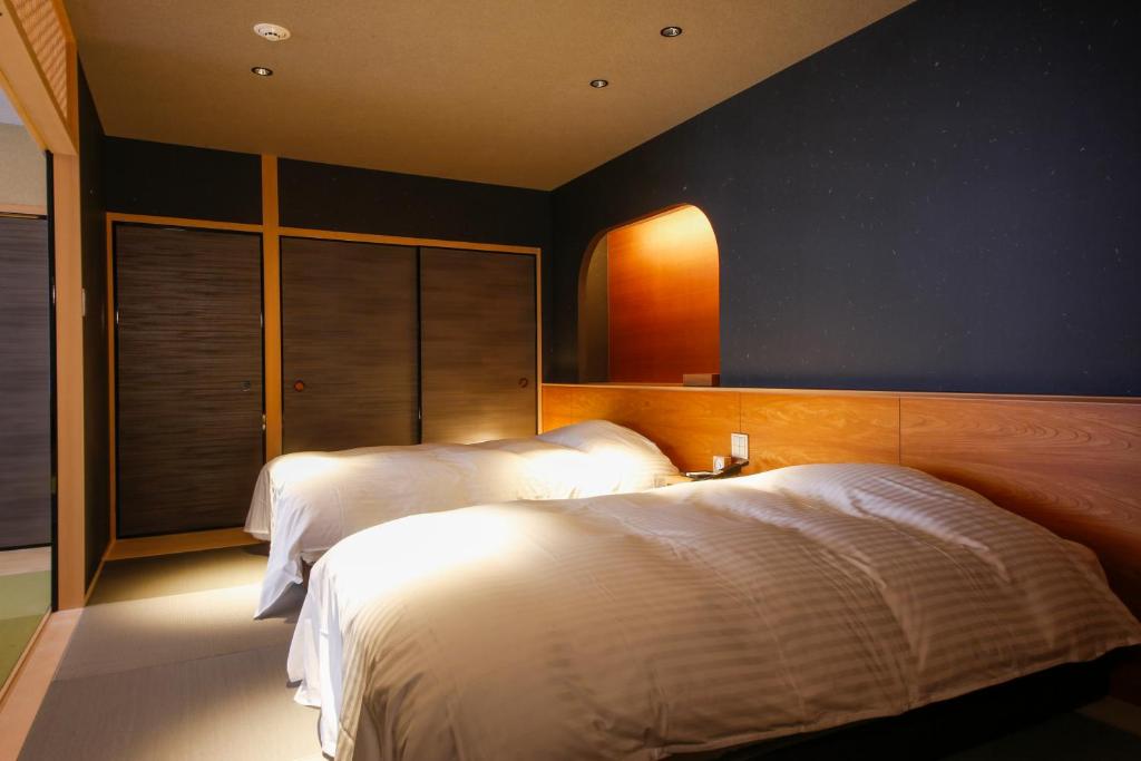 une chambre avec deux lits et un mur bleu dans l'établissement Hotel Honnoji, à Kyoto