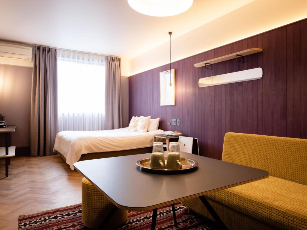 une chambre d'hôtel avec un lit, une table et des chaises dans l'établissement デザイナーズホテル アリス -Adult only-, à Sasebo