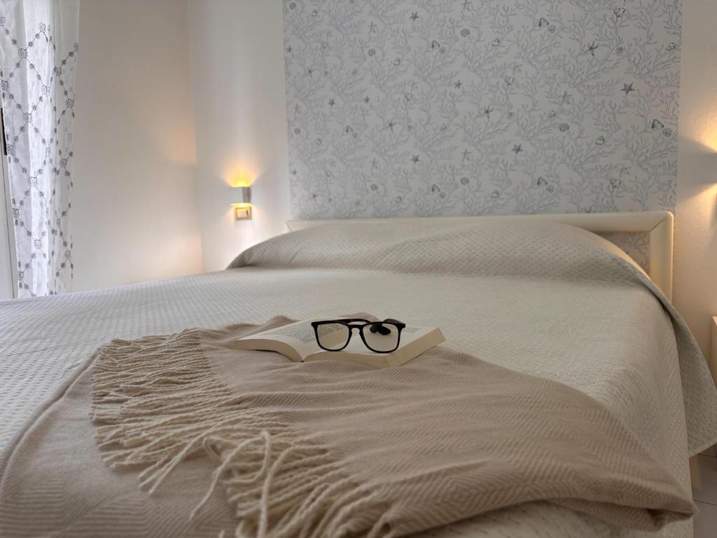 une paire de lunettes assise sur un lit dans l'établissement Residenza Pierre & Vacances Luni Mare, à Luni