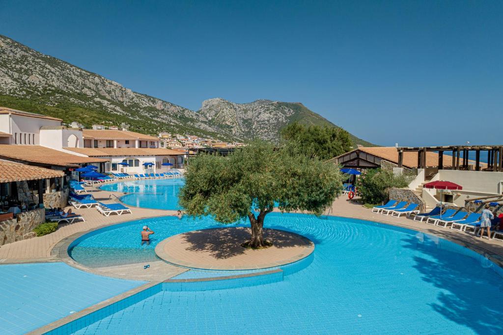 une grande piscine avec un arbre au milieu dans l'établissement Club Esse Cala Gonone, à Cala Gonone