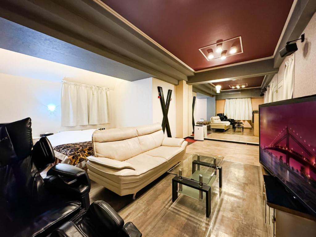 un salon avec un canapé et une télévision dans l'établissement Fire Hotel Nw, à Saitama
