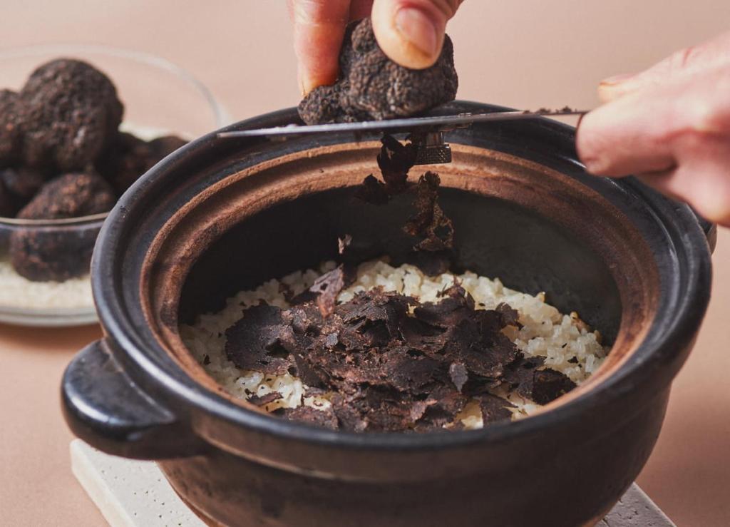 une personne tenant une paire de pinces sur un pot de nourriture dans l'établissement 源泉掛け流しの宿Albergo湯楽, à Yugawara