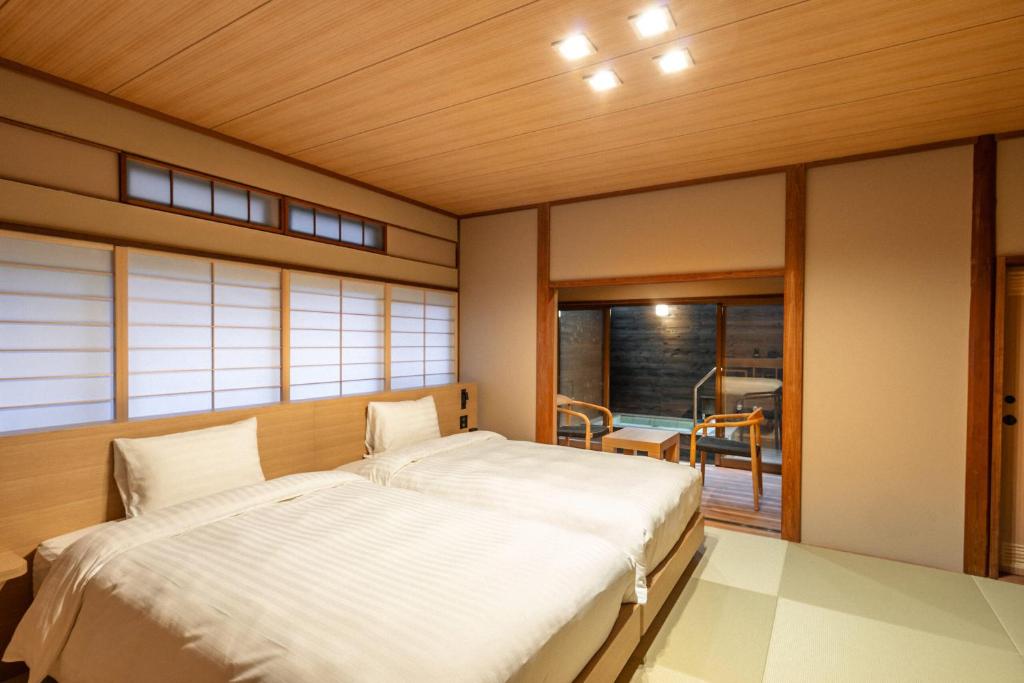 une chambre avec un grand lit et un balcon dans l'établissement 源泉掛け流しの宿Albergo湯楽, à Yugawara