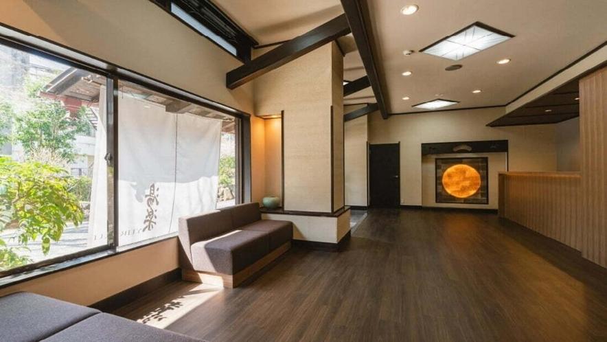 un salon avec un canapé et une grande fenêtre dans l'établissement 源泉掛け流しの宿Albergo湯楽, à Yugawara