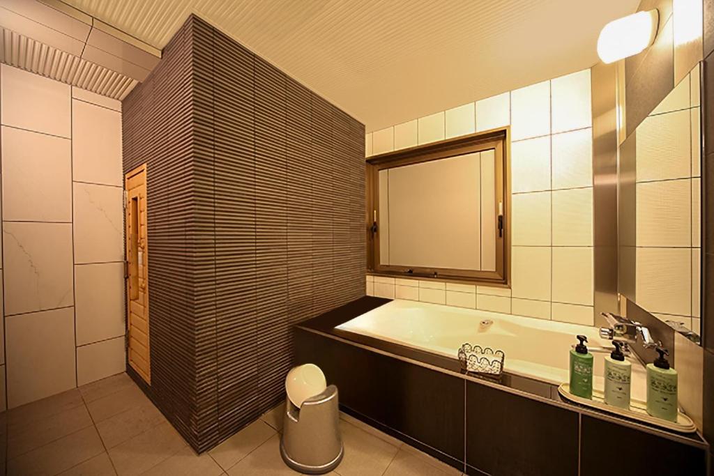 une salle de bain avec une baignoire, un lavabo et un miroir dans l'établissement Fire Hotel Nw, à Saitama