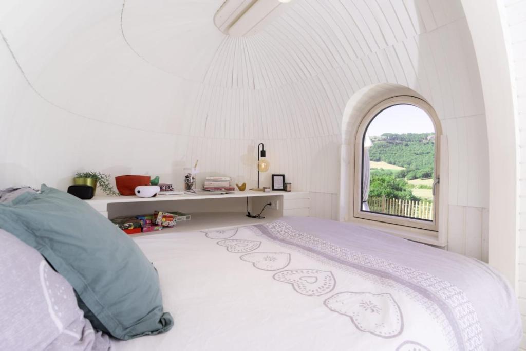 - une chambre blanche avec un lit et une fenêtre d'arche dans l'établissement La Cachottiere, à La Bastide-Pradines