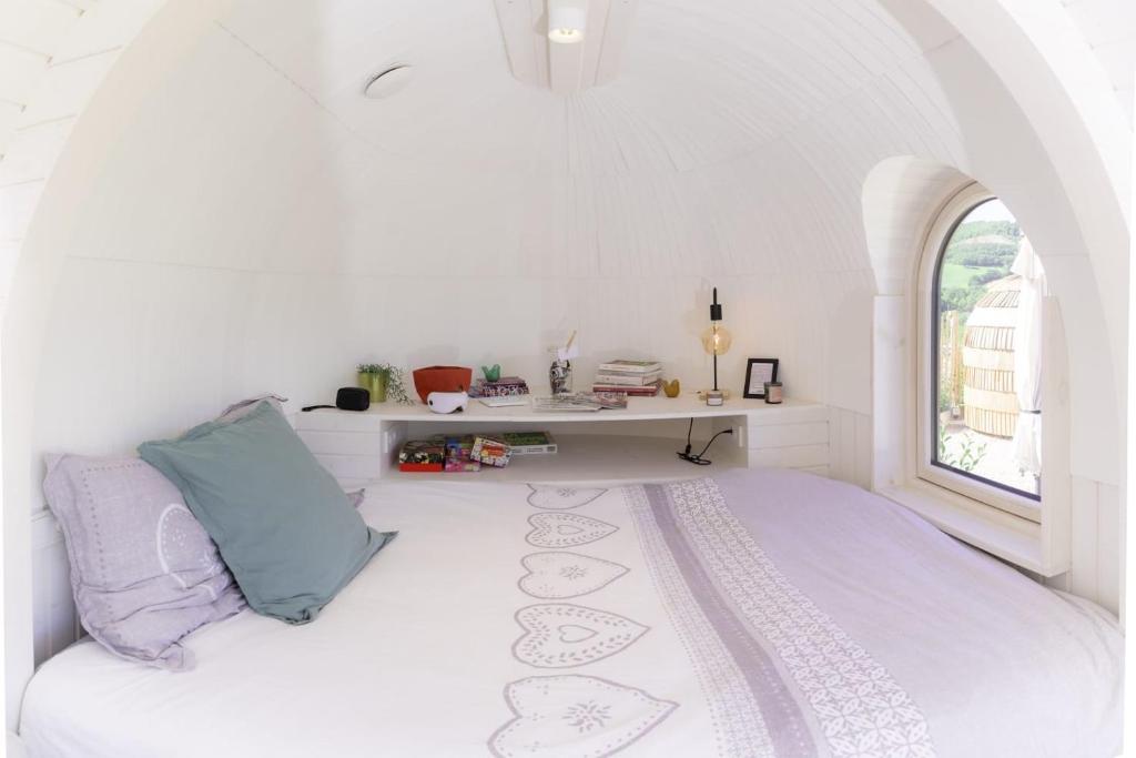une chambre blanche avec un lit et un bureau dans l'établissement La Cachottiere, à La Bastide-Pradines