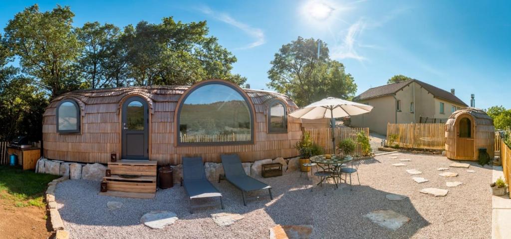 Cette maison dispose d'une terrasse avec des chaises et un parasol. dans l'établissement La Cachottiere, à La Bastide-Pradines