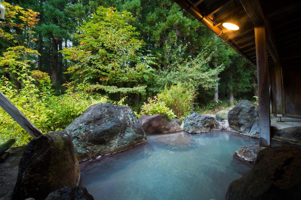 une piscine d'eau avec des rochers dans un jardin dans l'établissement Yunohirakan, à Takayama