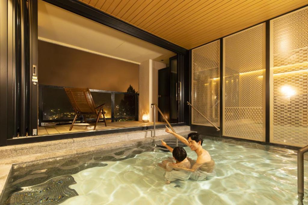 deux garçons jouant dans une piscine dans une maison dans l'établissement Ooedo Onsen Monogatari Premium Gero Honkan, à Gero