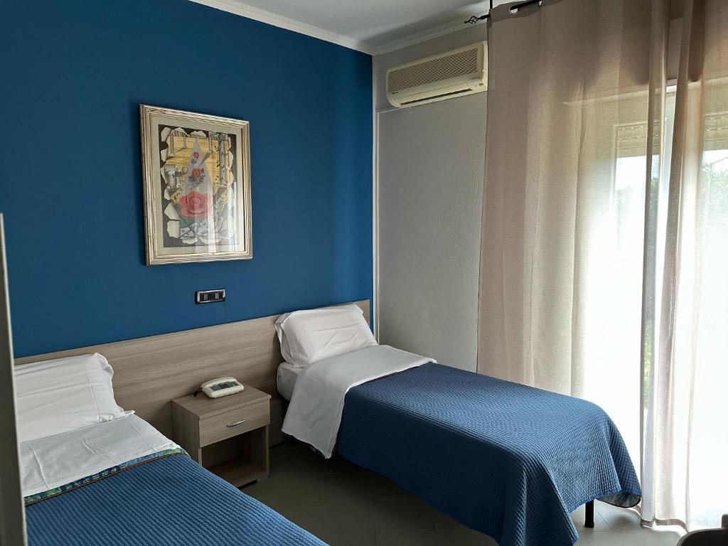 Cette chambre bleue comprend 2 lits et une fenêtre. dans l'établissement Hotel Costa Jonica, à Sellia Marina