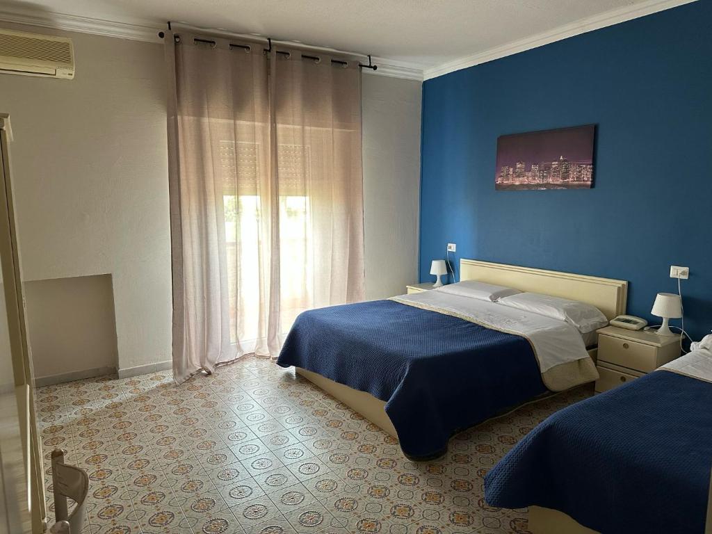 une chambre bleue avec deux lits et une fenêtre dans l'établissement Hotel Costa Jonica, à Sellia Marina