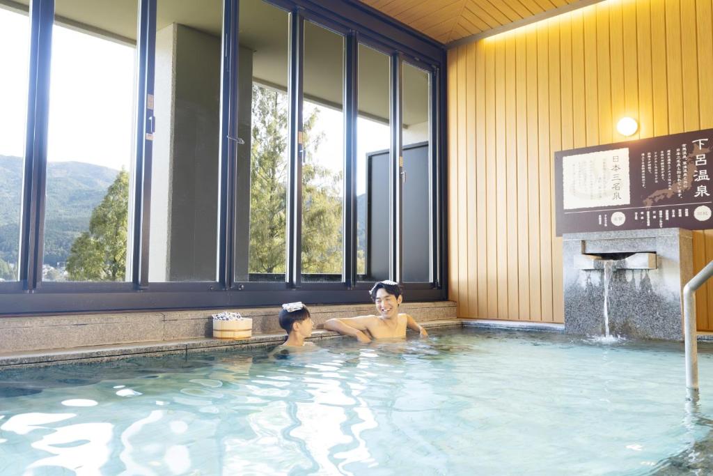 un homme et un enfant dans une piscine dans l'établissement Ooedo Onsen Monogatari Premium Gero Honkan, à Gero 25 autres photos