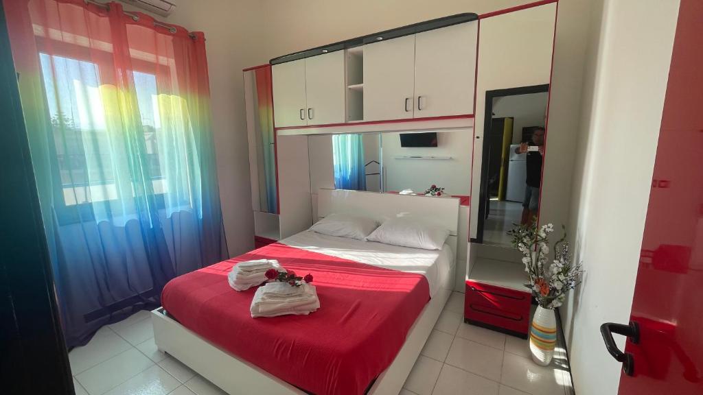 - une chambre dotée d'un lit avec des draps rouges et un miroir dans l'établissement LA BAIA DI NETTUNO Il Gatto e La Volpe, à Venetico