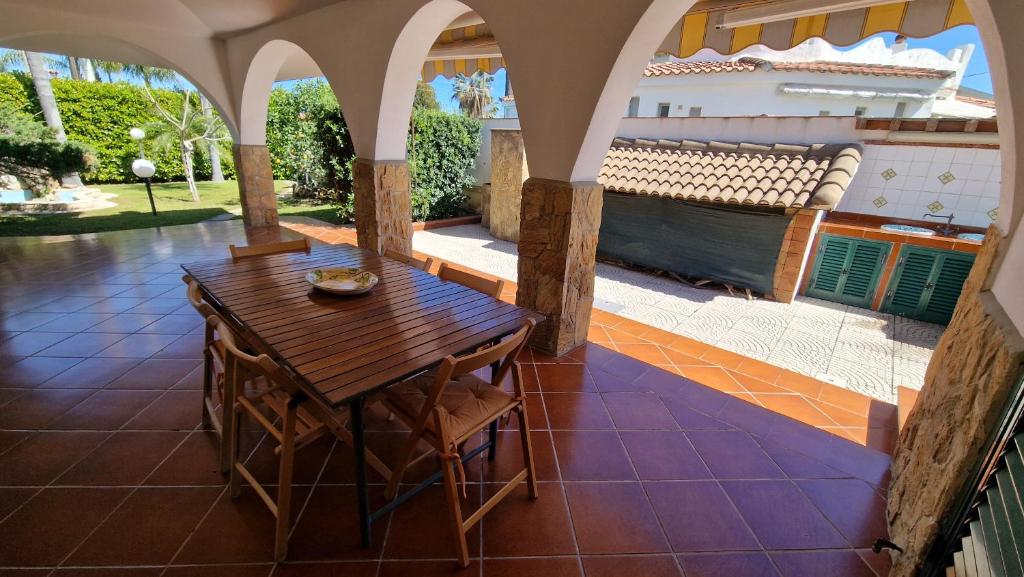 un porche avec une table et des chaises en bois sur un patio dans l'établissement Villa CARLOTTA, à Brucoli