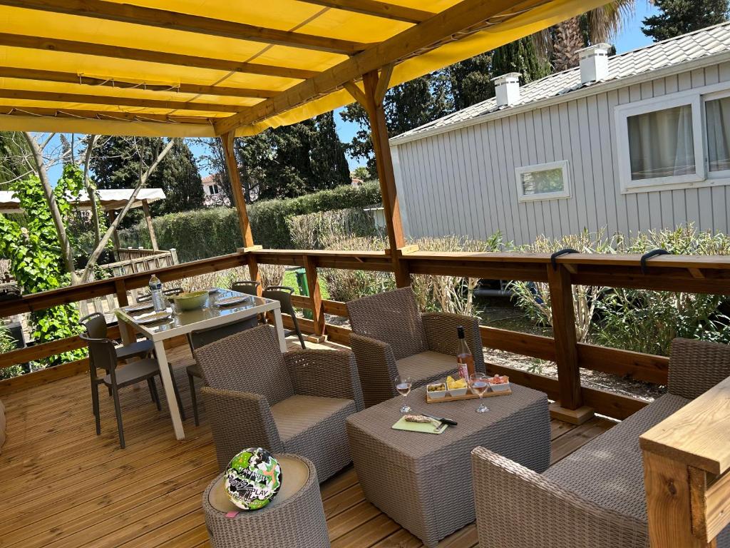 un patio avec une table et des chaises sur une terrasse dans l'établissement Mobile home sirène luxe Camping le Bosc 4 étoiles 3 chambres, à Saint-Cyprien
