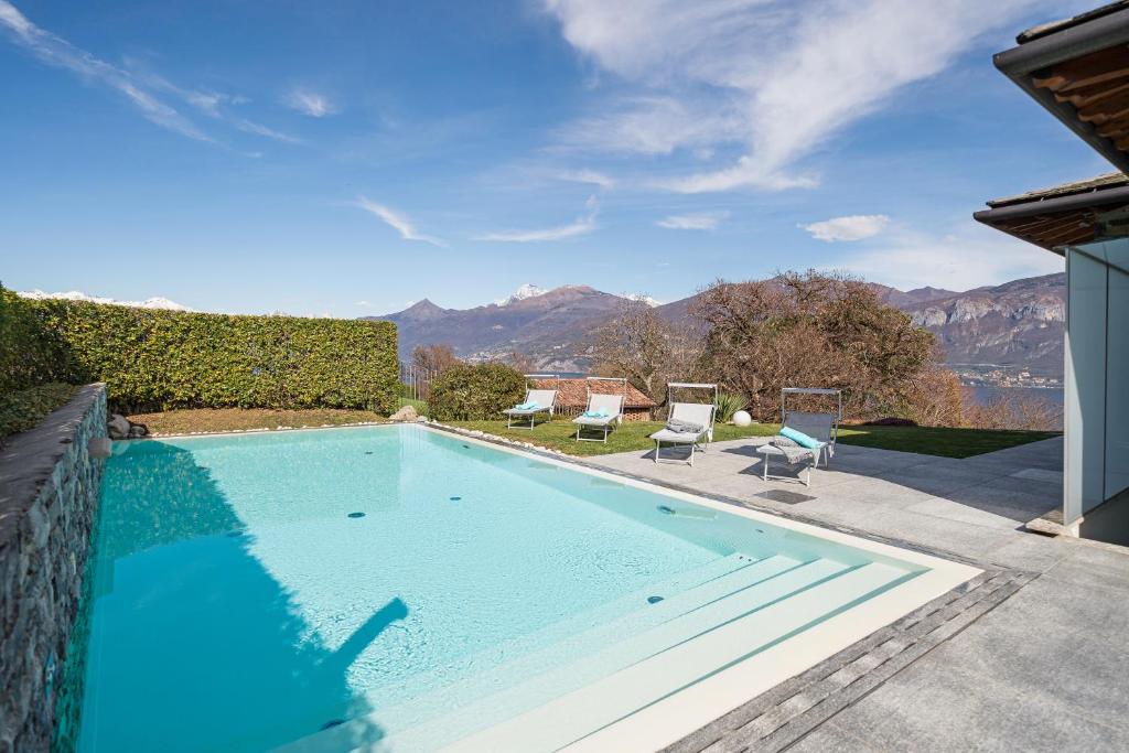 une grande piscine avec deux chaises longues et des montagnes dans l'établissement Villa Meraviglia, à Griante Cadenabbia