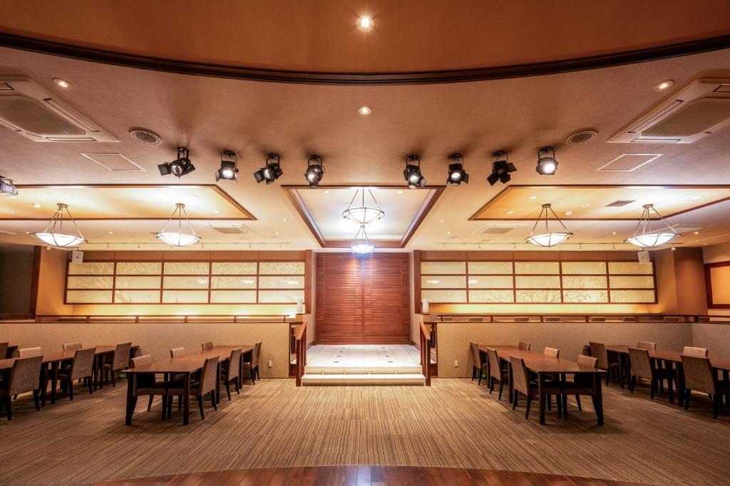 une salle à manger avec des tables, des chaises et des lumières dans l'établissement Yumoto Kanko Hotel Saikyo, à Nagato