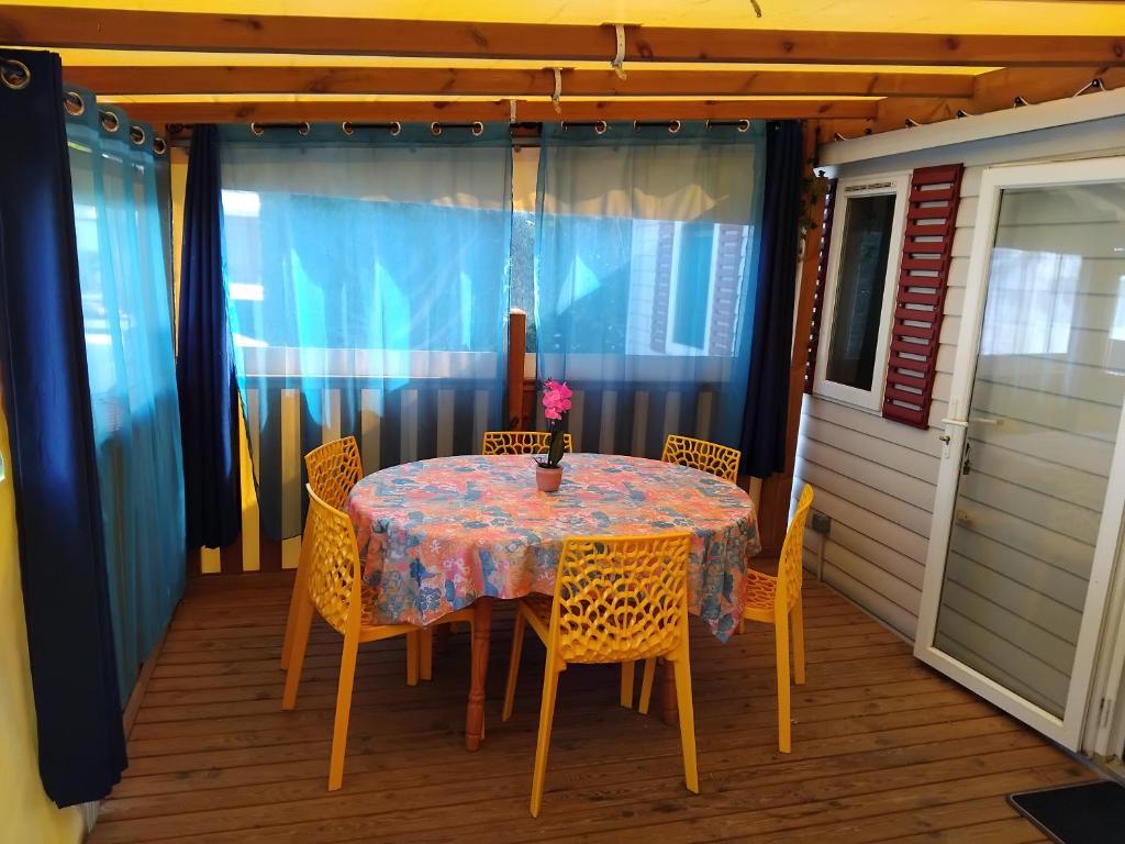 - une table et des chaises sur une terrasse couverte munie d'une table et de chaises dans l'établissement MOBIL HOME GLAMPING CONFORT D'UN HOTEL SANS LES CONTRAINTES PISCINE PROMOTION SEPTEMBRE 3 CHAMBRES - 2 SdB -climatisé - 300m de la mer - piscine - parking -, à Hyères