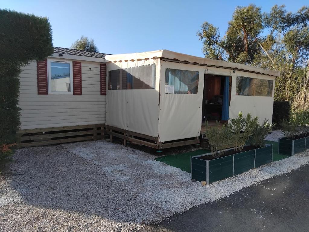 un abri blanc avec une véranda et quelques plantes dans l'établissement MOBIL HOME GLAMPING CONFORT D'UN HOTEL SANS LES CONTRAINTES PISCINE PROMOTION SEPTEMBRE 3 CHAMBRES - 2 SdB -climatisé - 300m de la mer - piscine - parking -, à Hyères 5 autres photos