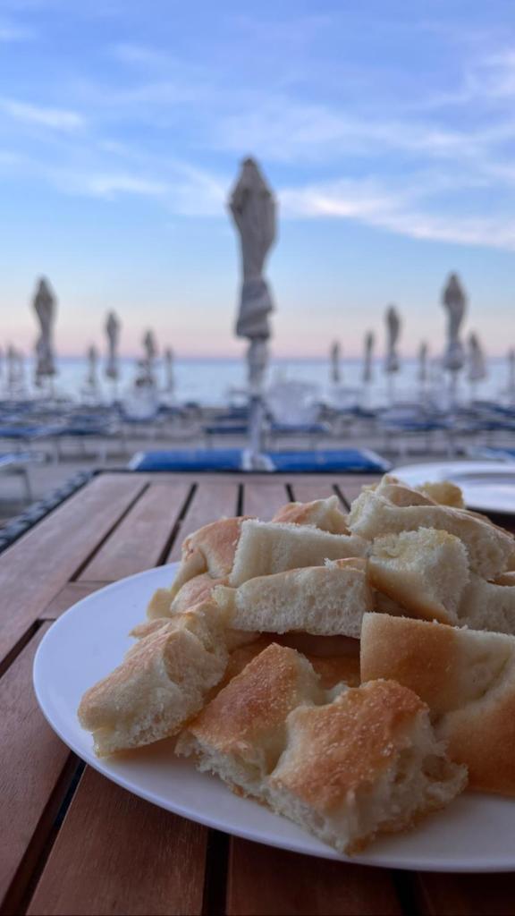 - une assiette de pain sur une table avec vue sur la plage dans l'établissement Hotel Gandolfo, à Alassio