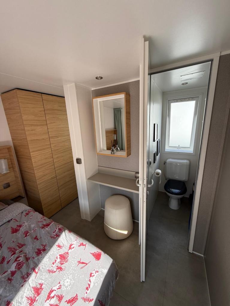 - une petite salle de bains avec un lit et un miroir dans l'établissement Camping 5 étoiles domaine de la Yole, à Vendres