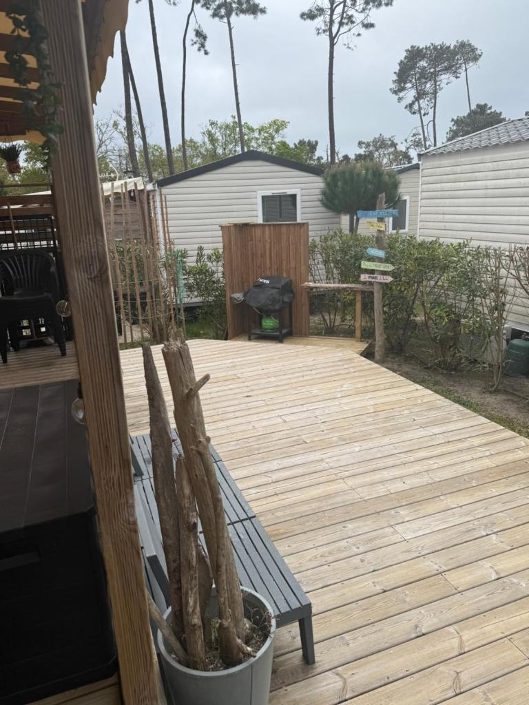 une terrasse couverte avec un banc sur une terrasse en bois dans l'établissement Mobilhome 6-8 pers Cap Ferret, à Lège-Cap-Ferret