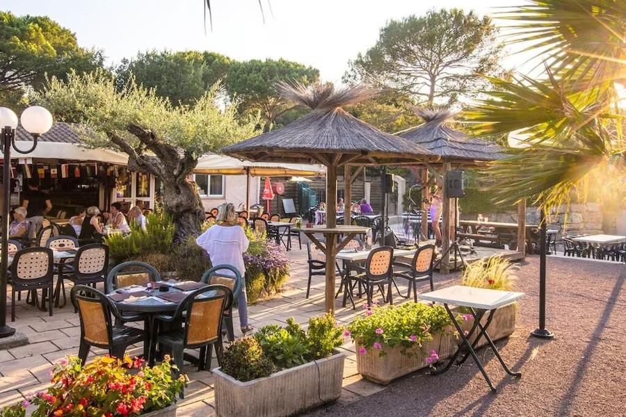 un patio avec des tables et des chaises et des tables. dans l'établissement Mobile home 6-pers Camping Leï Suves-Côtes d'Azur-including airco, à Roquebrune-sur Argens