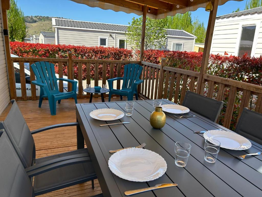 une table en bois avec des assiettes et des chaises sur une terrasse dans l'établissement Le Paradis du Rhône - mobilhome moderne et confortable, à Condrieu