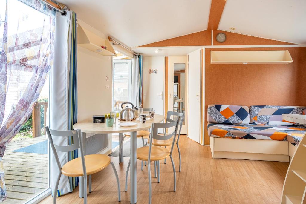 Cette petite chambre comprend une table, des chaises et un lit. dans l'établissement Mobilhome - piscines - terrasse, à Angles