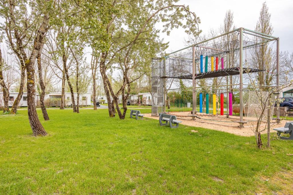 un groupe de bancs dans un parc arboré dans l'établissement Mobilhome - piscines - terrasse, à Angles