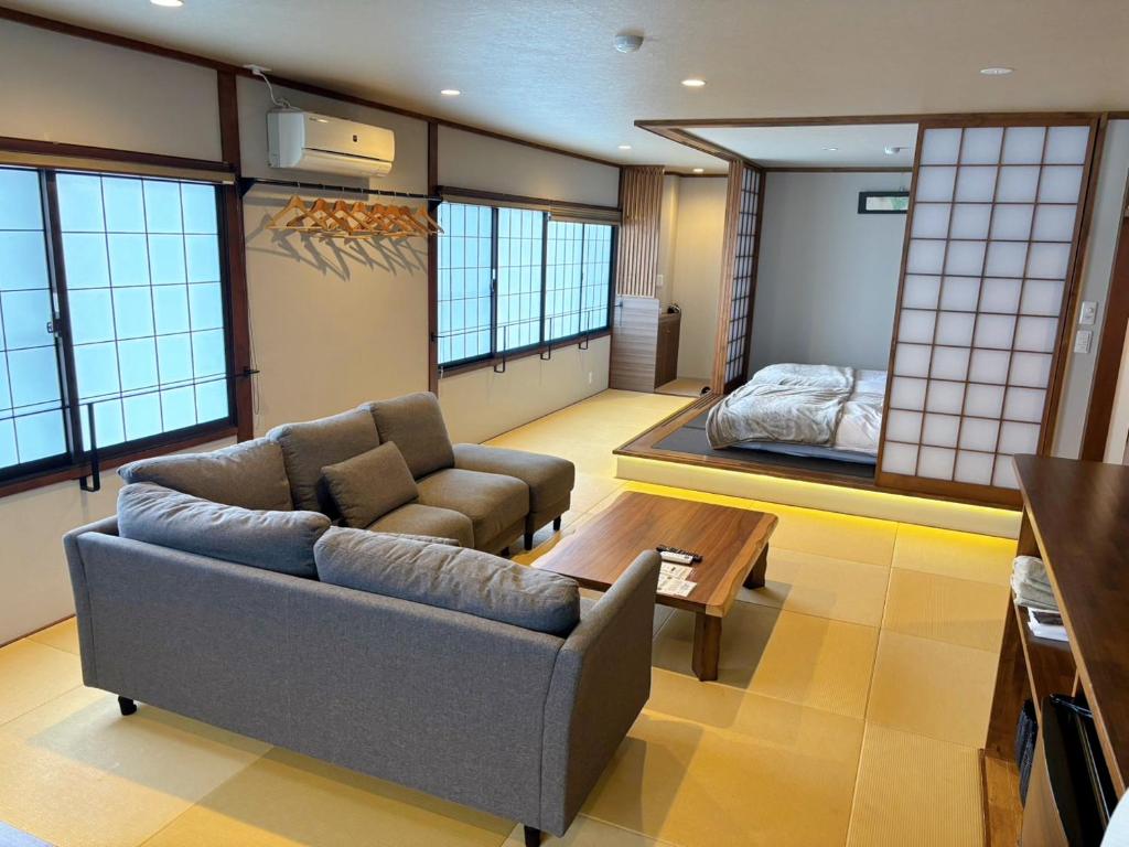 un salon avec un canapé et un lit dans l'établissement Nozawa Onsen Azegamikan, à Nozawa Onsen