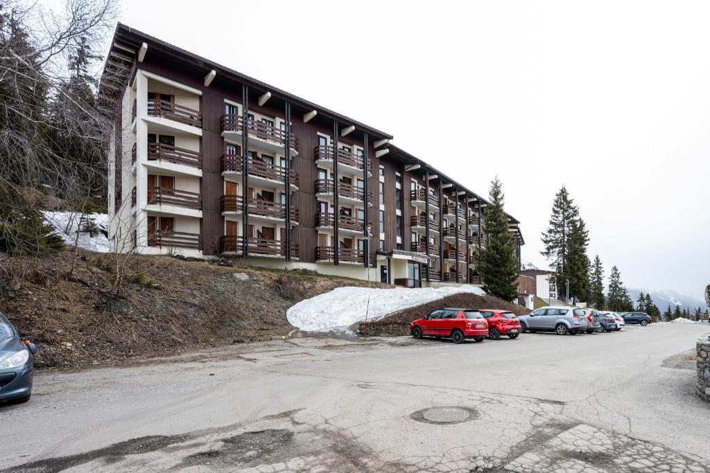 un grand bâtiment avec des voitures garées devant dans l'établissement Les Bouquetins A, à La Rosière